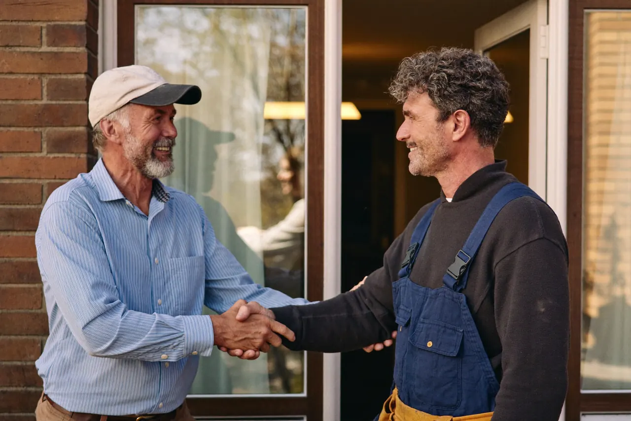 A homeowner shaking hands with a window fitter on the doorstep