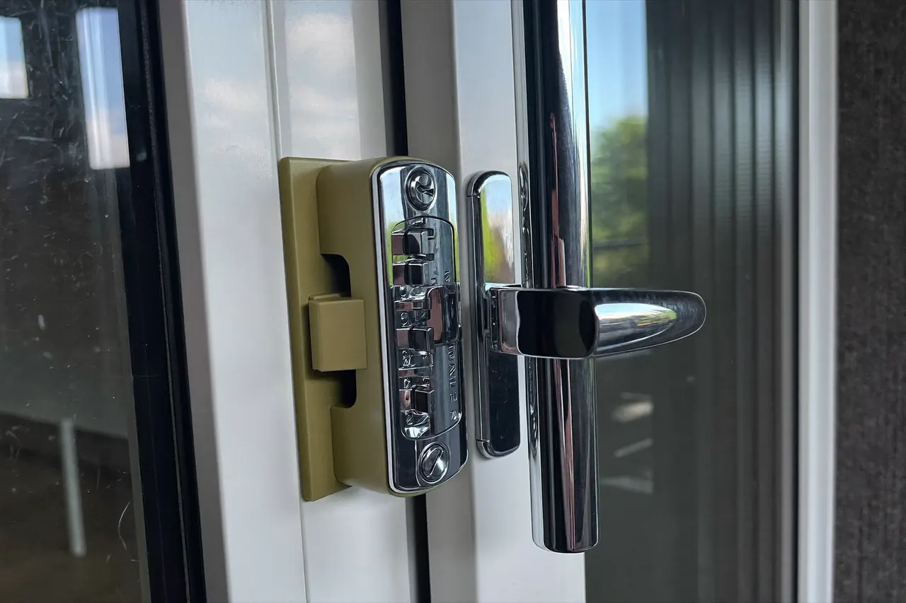 Close-up of a chrome handle and lock on a white uPVC window